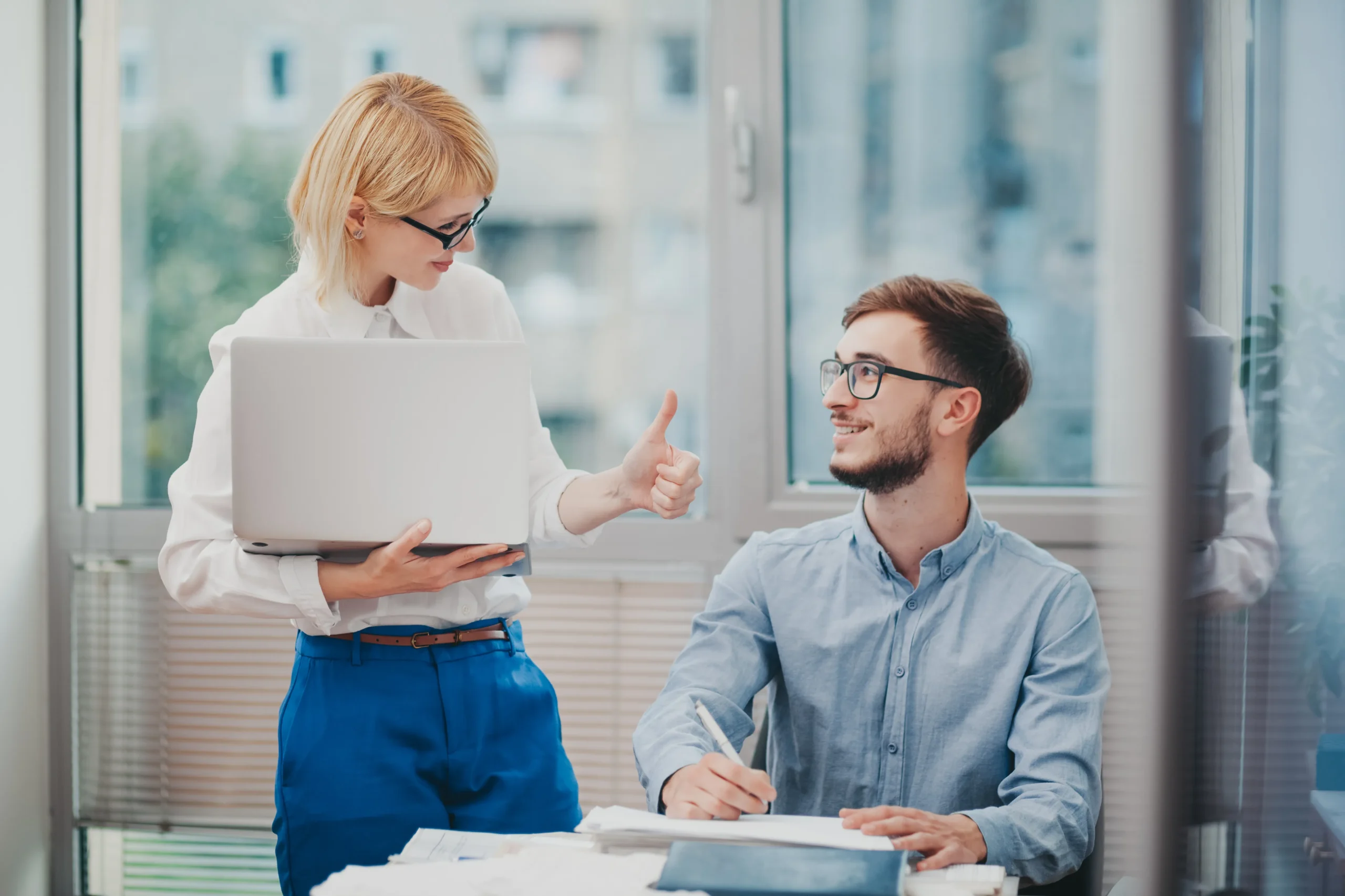 Two coworkers in office sharing positive feedback, symbolizing 360-degree performance review and collaboration."