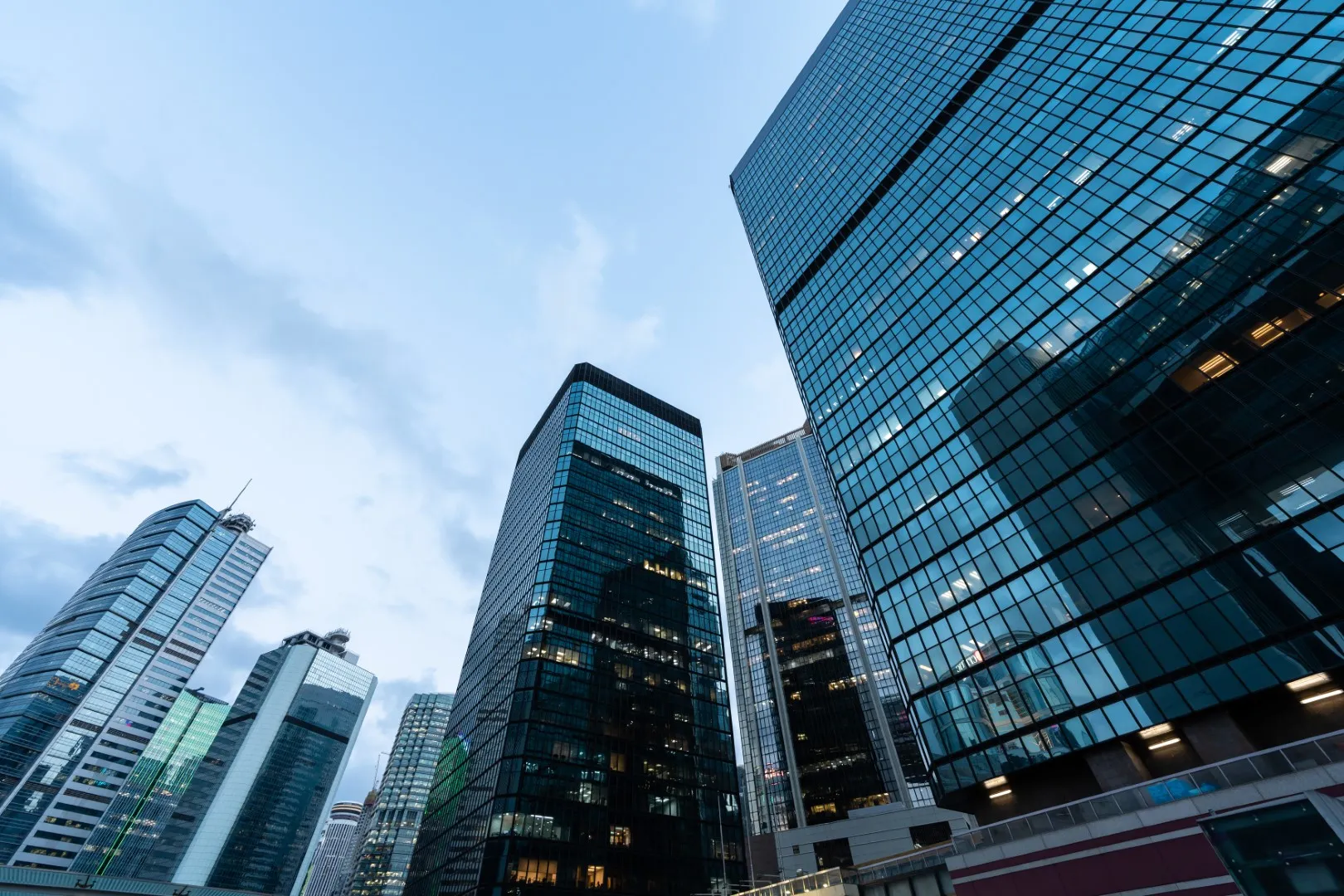 Tall glass skyscrapers and modern office buildings in a financial district under a clear blue sky.
