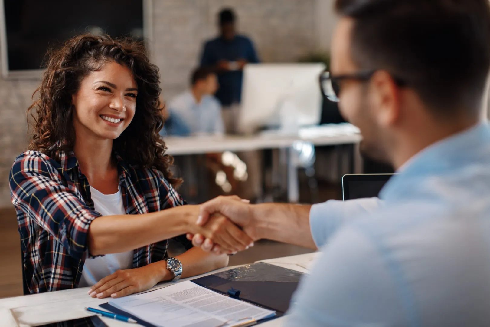 Candidate and interviewer shaking hands across a desk in an office setting, representing the start of a new internship role at Retensa