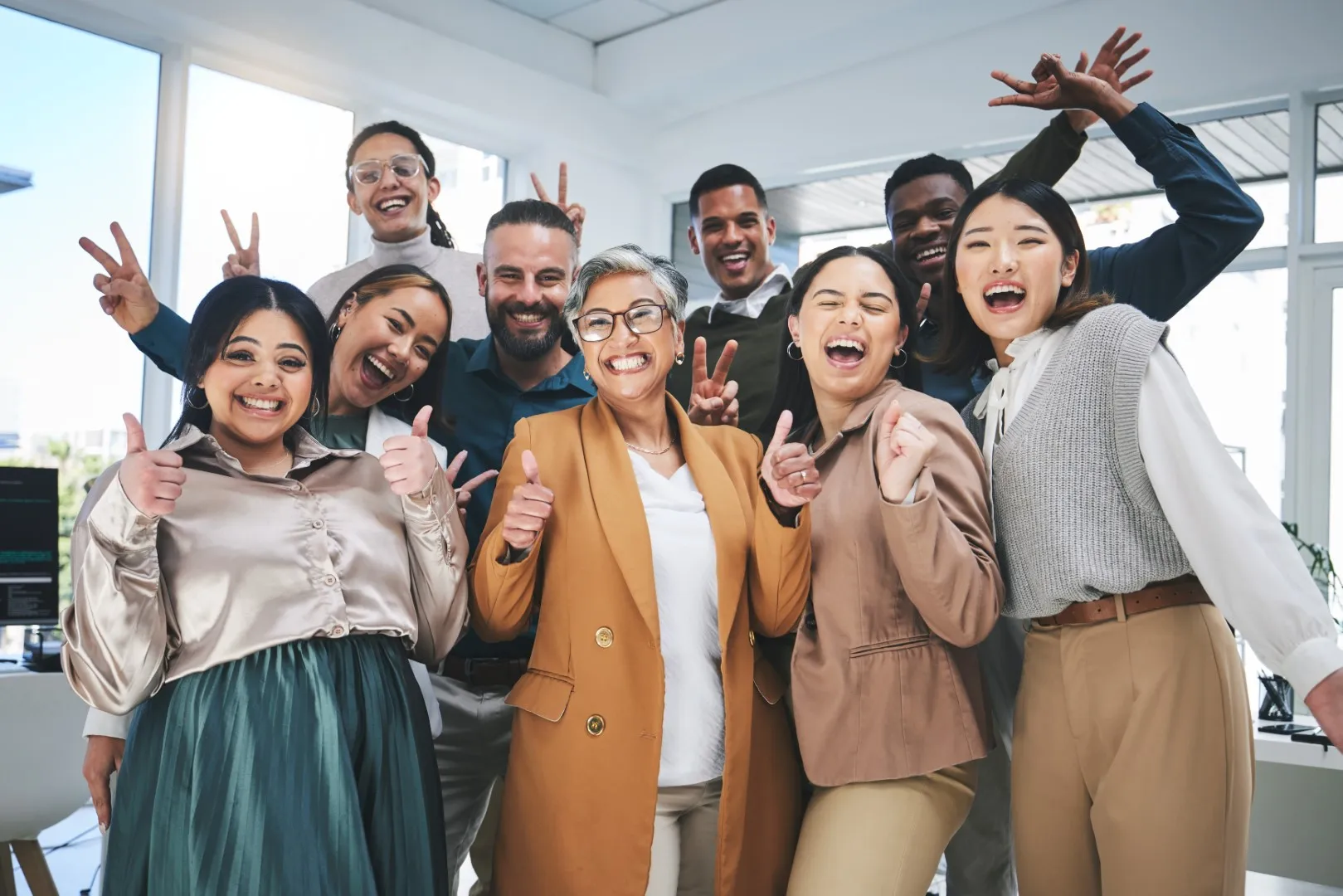Group of coworkers posing together in a bright office, celebrating teamwork and a positive workplace culture