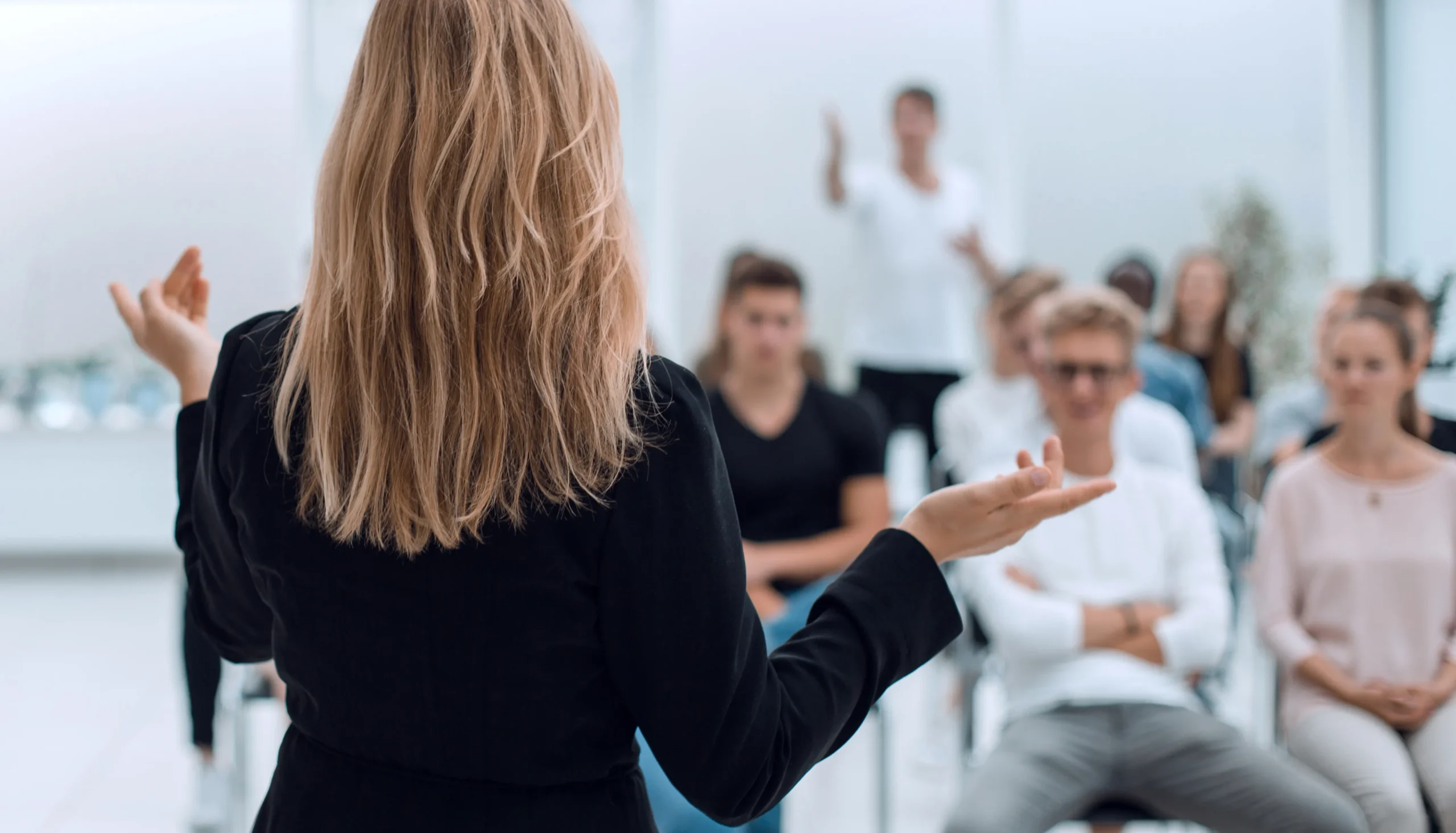Instructor leading a retention skills training session, speaking to a group of employees seated and engaged in the discussion